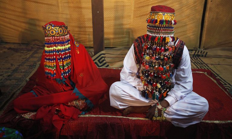 A bride and groom sit together during a mass marriage ceremony held in Karachi